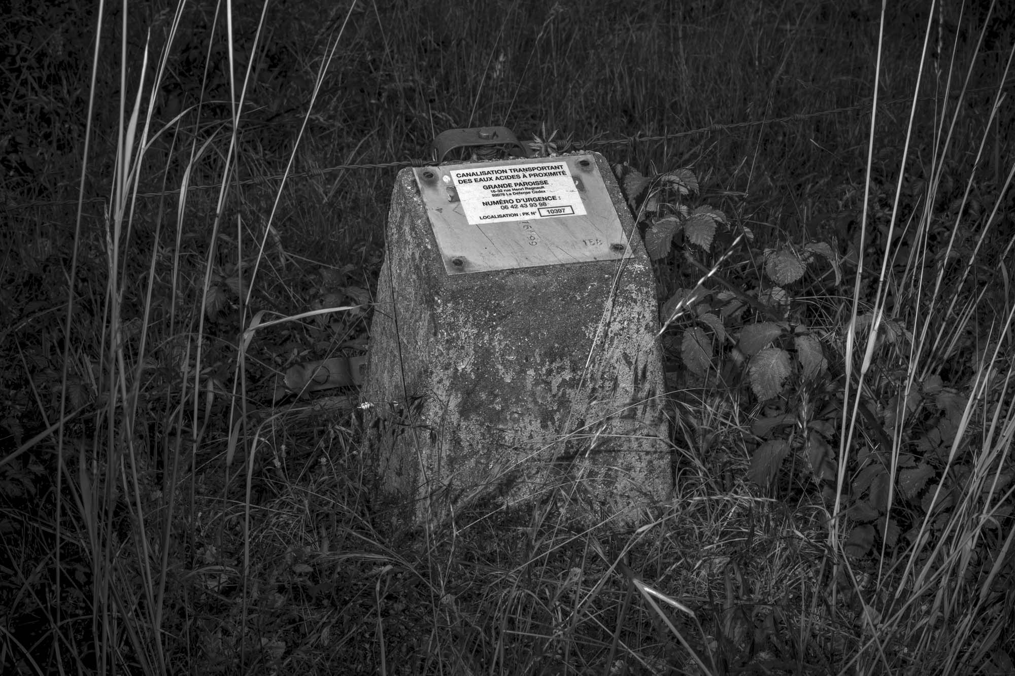 Borne signalant le passage d'une canalisation d'eau acide près du site de confinement du phosphogypse à Anneville-Ambourville. Normandie (FR)